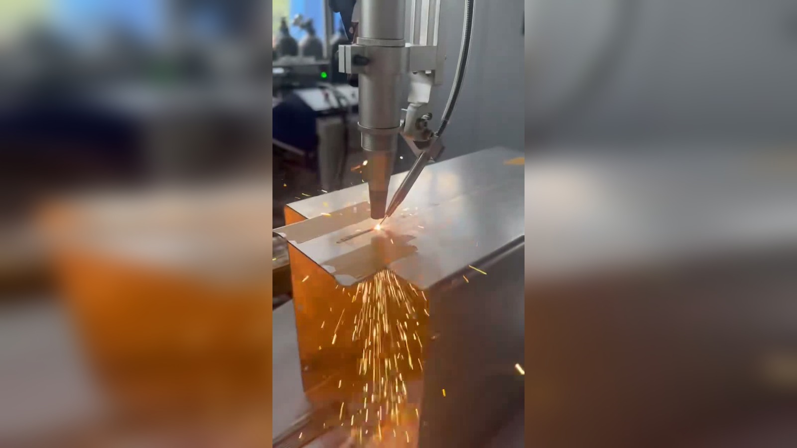 Robot laser welding a battery-box-style metal enclosure with visible sparks