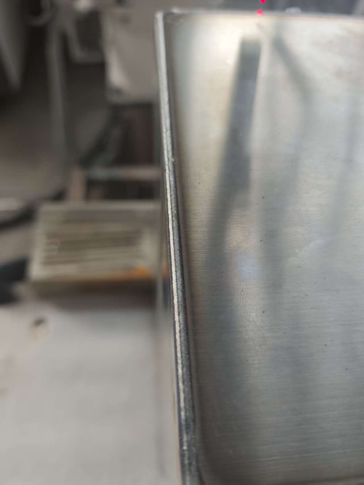 Close-up weld seam detail on a battery-box-style metal sample